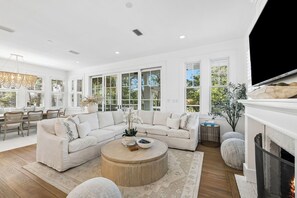 Un salon moderne avec un canapé d’angle, une table basse ronde et une cheminée.
