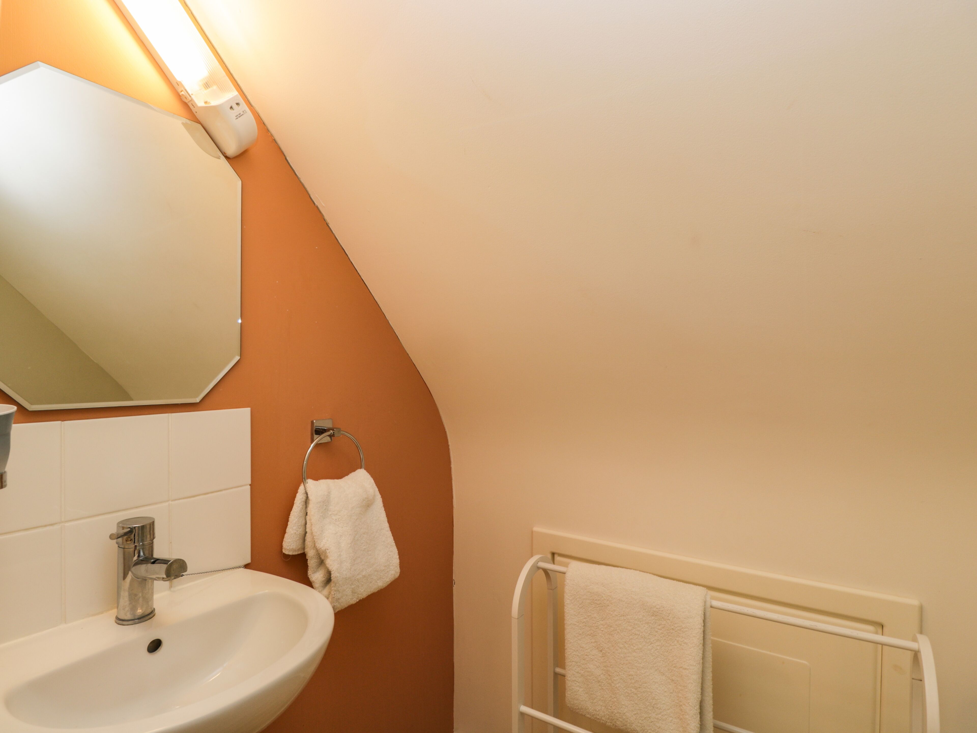 Un bagno con lavandino, specchio, asciugamano e porta asciugamani.