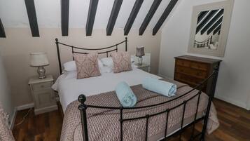 Un dormitorio con cama, mesitas de noche, cómoda y espejo en la pared.