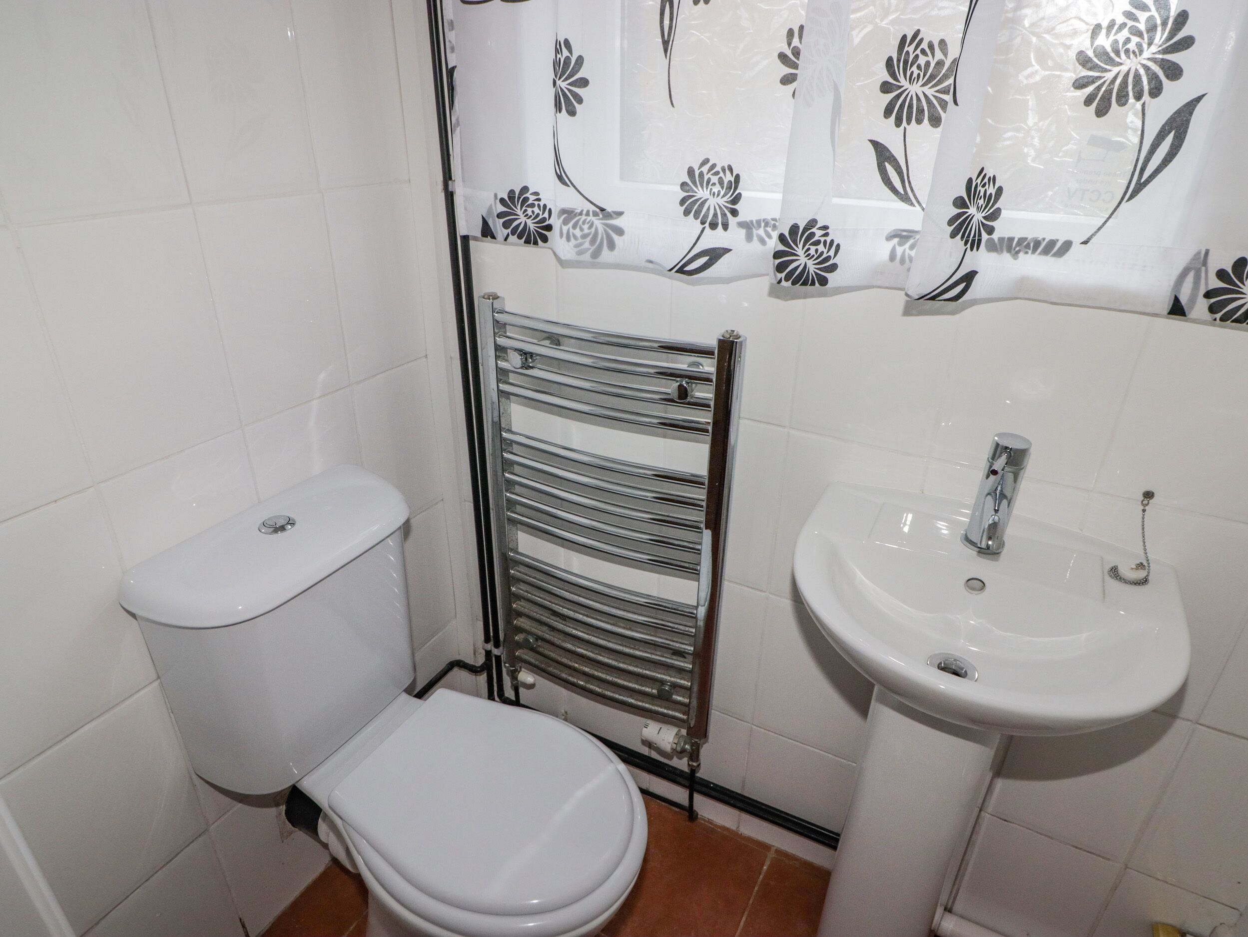 A small bathroom with a toilet, a towel rack, and a sink.