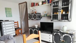 A cozy living room with a wooden dining table, a television, and a bookshelf filled with books and decorative items. - Les Motes 7º, Solo Familias ! (Xeraco Playa)