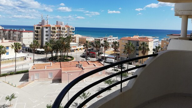 A view from a balcony overlooking a coastal cityscape with buildings, palm trees, and a clear blue sky. - Les Motes 7º, Solo Familias ! (Xeraco Playa)