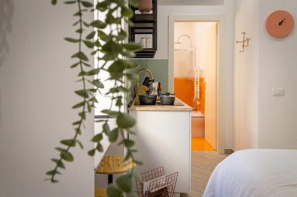 Une pièce de taille modeste comprenant un lit, une petite kitchenette et une salle de bain.