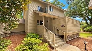A two-story house with a covered porch and a staircase leading to the entrance. - An Inspired Renovation Perfect for Your Next Family Getaway! (Hilton Head)