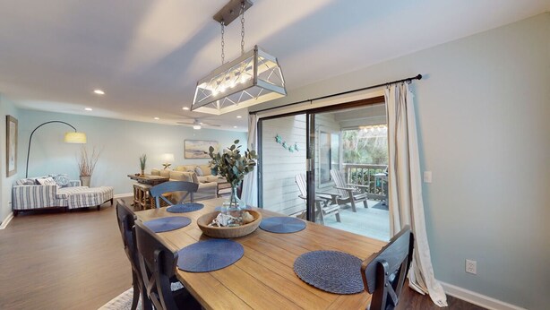 Un coin repas avec une table en bois, des sets de table bleus et un luminaire suspendu.