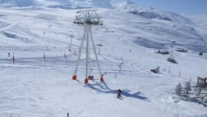 A ski lift with a cable system, a snowy mountain slope, and skiers.