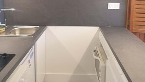 A compact kitchen with a microwave, sink, and dishwasher.