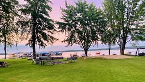 Un parco sul lago con tavoli da picnic, un braciere e un'area giochi con altalene.