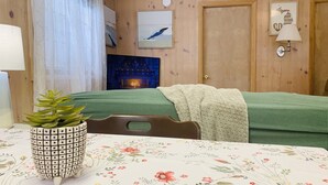 Un'accogliente stanza con un letto, un tavolo con una pianta in vaso, un camino e pareti in legno.