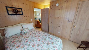 Un dormitorio con cabecera de madera, colcha estampada y un armario de madera.