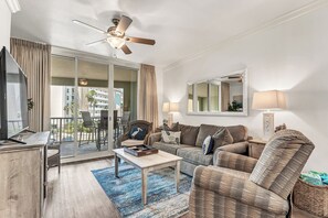 A living room with a sofa, armchair, coffee table, TV, and a ceiling fan. - Azure 222/Great Pools/Gorgeous Beach/Beach Service/Resort Renovated 2025 (Fort Walton Beach)
