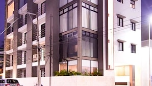 A multi-story building with a modern architectural design, featuring large windows and balconies. - Modern Stay - Rooftop Pool - Walk to Beach & 5th (Playa del Carmen)