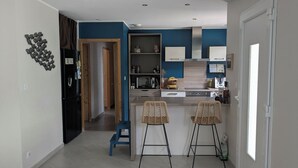 A modern kitchen with a microwave, sink, and two bar stools.