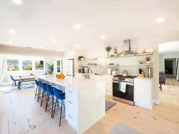 A modern kitchen with a central island, bar stools, a stove, and a sink. - Renovated Downtown Great Barrington House (Great Barrington)