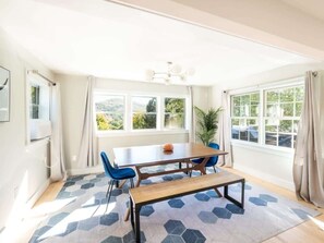 A bright room with a large window, a table with chairs, and a bench. - Renovated Downtown Great Barrington House (Great Barrington)