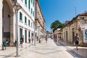Une rue piétonne bordée de bâtiments historiques, où se côtoient différents styles architecturaux, et où le ciel est dégagé.