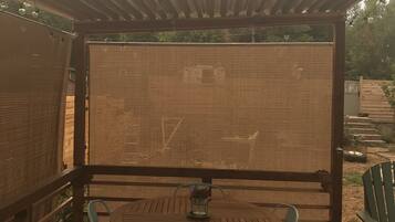 Un espacio de estar al aire libre cubierto con una mesa, sillas, una malla y un piso de madera.