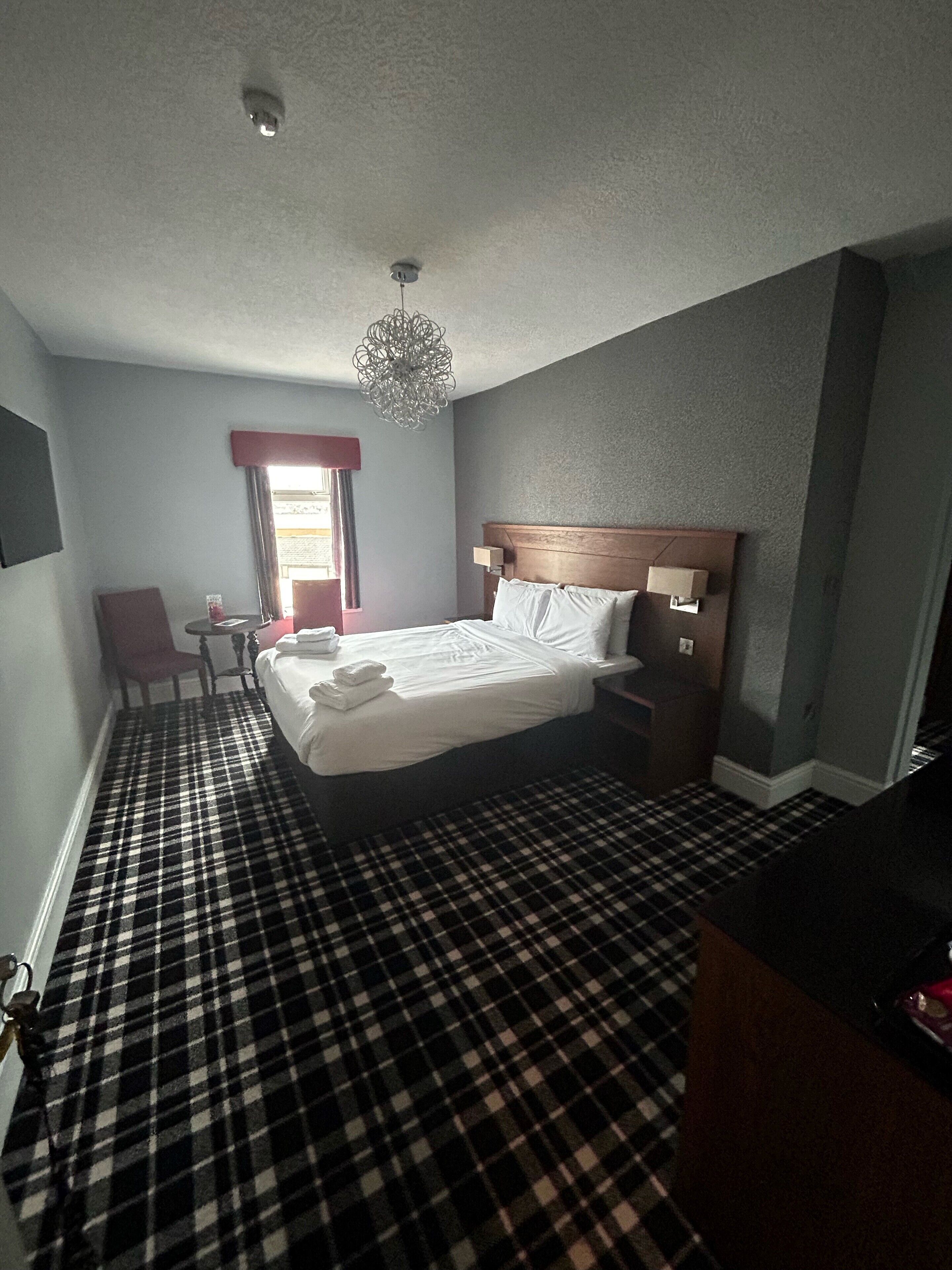 A hotel room with a bed, a chair, a desk, and a television.
