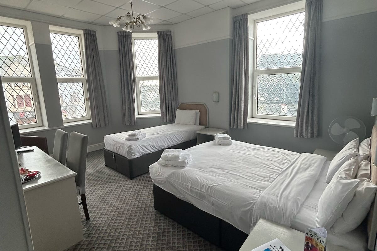 A hotel room with two beds, a desk, and a chair.