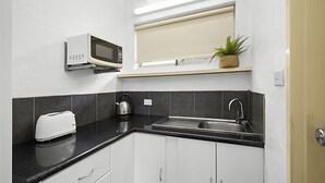 Une cuisine compacte équipée d’un four à micro-ondes, d’un grille-pain, d’une bouilloire et d’un évier.