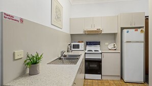 A compact kitchen with a sink, microwave, stove, and refrigerator. There's a 'Thank you for not Smoking' sign on the wall.