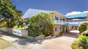 A motel with a signboard, a covered walkway, and surrounding greenery.