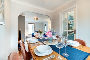 A dining area with a long wooden table set for six, a blue chair, and a vase with flowers. - 2 Bed in Braunton (oc-stepco) (Braunton)