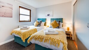 A hotel room with two beds, each with a yellow fringe blanket, a window, a headboard, a nightstand, and a wall-mounted lamp. - 2 Bed in Braunton (oc-stepco) (Braunton)