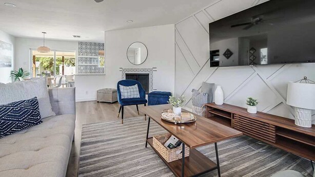 A modern living room with a sofa, a blue armchair, a coffee table, and a fireplace. - Charming Getaway 4 Min to Downtown-Hot Tub, Firepit Grill (Fredericksburg)