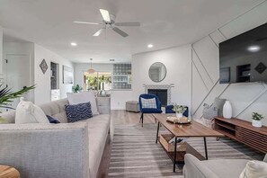 A modern living room with a sofa, armchairs, a coffee table, and a fireplace. - Charming Getaway 4 Min to Downtown-Hot Tub, Firepit Grill (Fredericksburg)