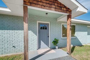 A house with a light blue brick exterior, a white door, and a small potted plant on the porch. - Charming Getaway 4 Min to Downtown-Hot Tub, Firepit Grill (Fredericksburg)