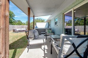 Un patio al aire libre con una mesa y sillas, una zona cubierta y vistas al jardín trasero.