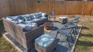 A backyard with a wicker sofa set, two chairs, a fire pit, and a small table. - Charming Getaway 4 Min to Downtown-Hot Tub, Firepit Grill (Fredericksburg)