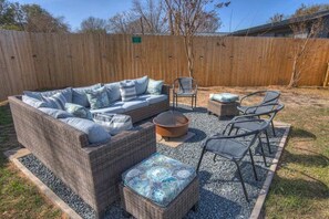 A backyard with a wicker sofa set, two chairs, a fire pit, and a small table. - Charming Getaway 4 Min to Downtown-Hot Tub, Firepit Grill (Fredericksburg)