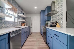 Una cocina moderna con armarios azules, electrodomésticos de acero inoxidable y un salpicadero con diseño.