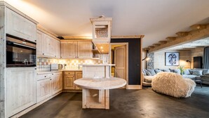 Una cocina con armarios de madera, una mesa redonda y un otoman suave.