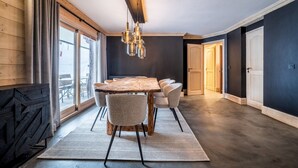 Un comedor con mesa y sillas de madera, una lámpara colgante y vistas amplias a través de grandes ventanales.