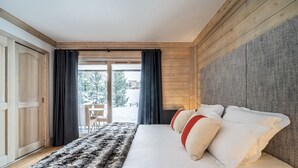 Un dormitorio con una cama grande, paredes de madera, un cubrecama de piel y vistas al exterior.