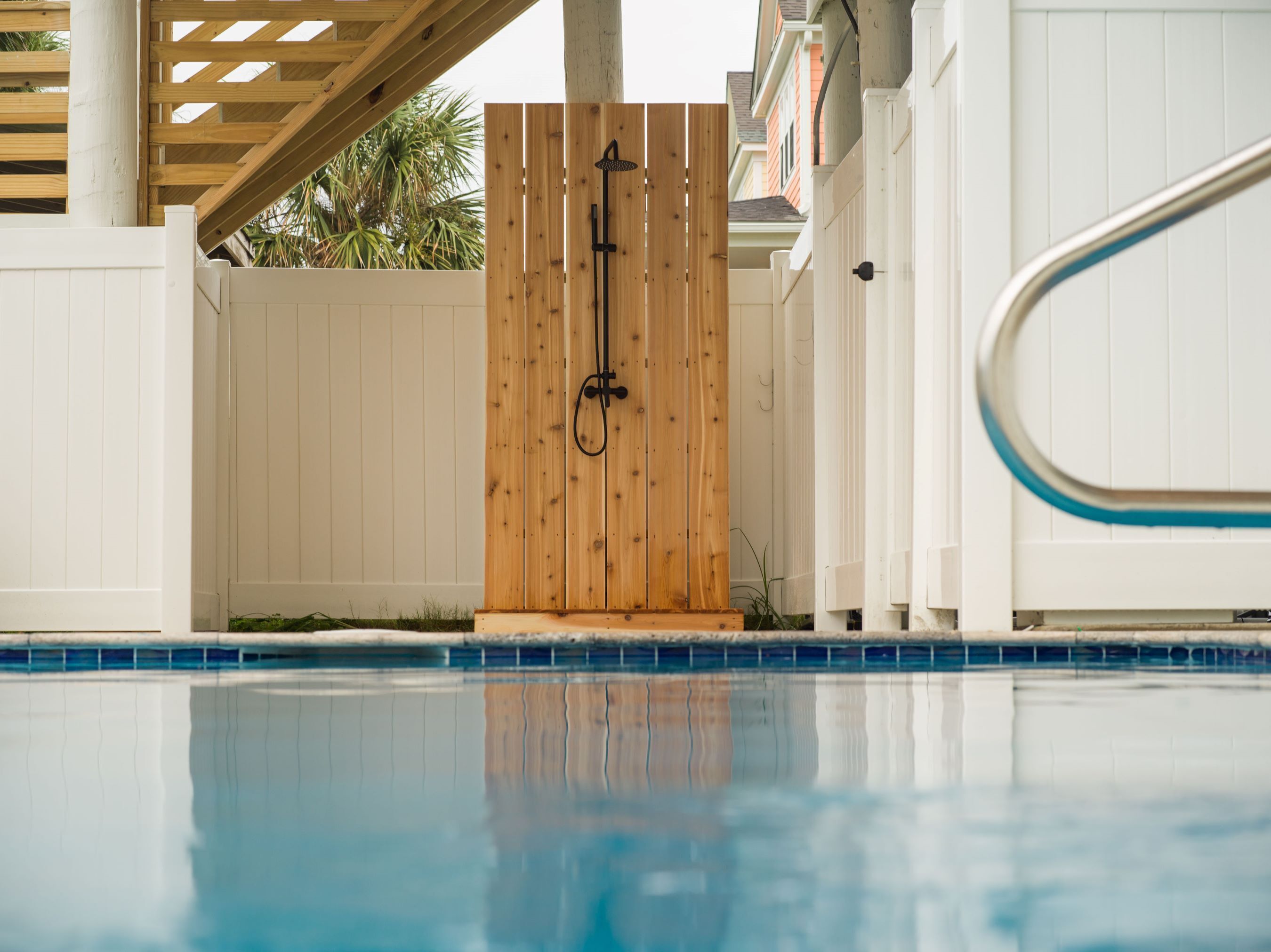 A wooden gate leading to a pool area with a clear blue pool.