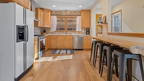 Eine moderne Küche mit Holzausstattung, Edelstahlgeräten und einer Bar mit Hockern.