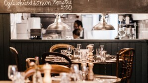 A restaurant interior with a chalkboard menu listing various dishes and prices. - The Bull Inn (Totnes)