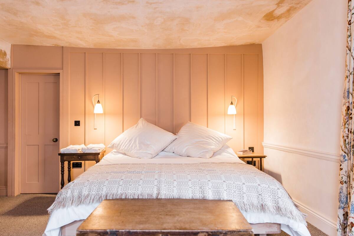 A bedroom with a large bed, two bedside tables, and a wooden bench.
