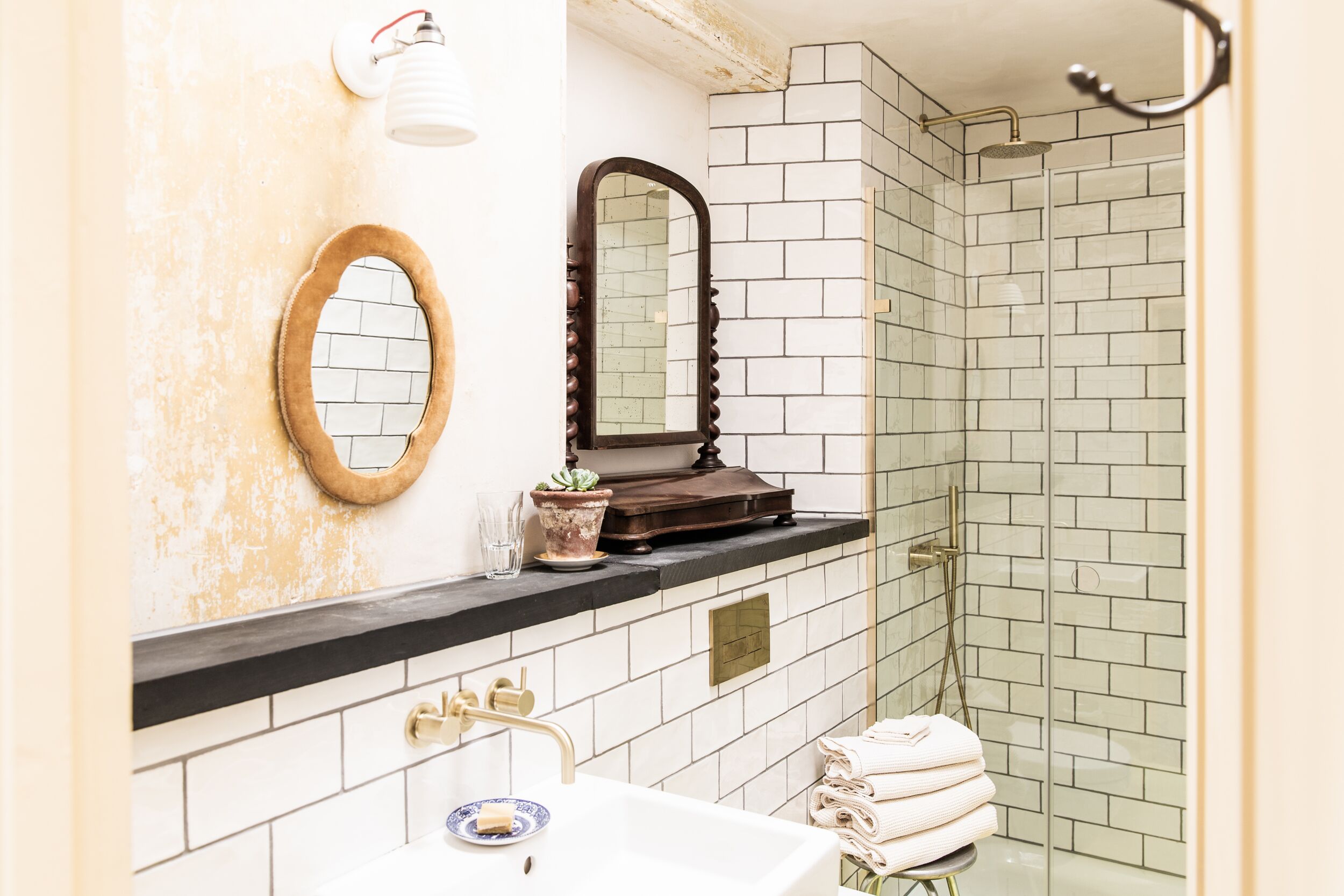 Un bagno con un lavandino bianco, uno specchio e una cabina doccia con piastrelle bianche.