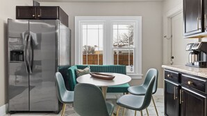 Et moderne køkken med et indbygget køleskab, et spisebord med fire stole, og en væg i teal farve.