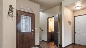 A hallway with a wooden door, a welcome sign, a light fixture, and a rug.