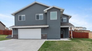 A two-story house with a garage, a front yard, and a wooden fence.