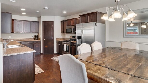 A modern kitchen with dark wood cabinets, stainless steel appliances, and a large island with a sink.