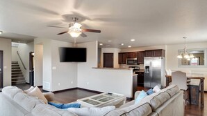 A modern living room with a sectional sofa, a glass coffee table, and a ceiling fan.