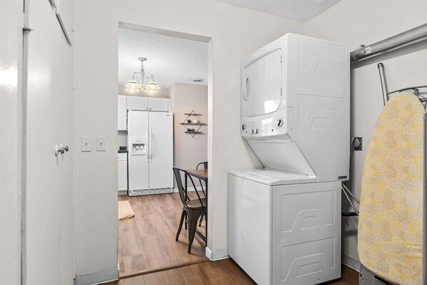 A compact kitchen with a refrigerator, a washing machine, and a dining area with a chair and table.