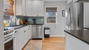 A modern kitchen with white cabinets, stainless steel appliances, and a window with blinds. - Walk to Parks- Pet Friendly-Top Neighborhood (Rapid City)